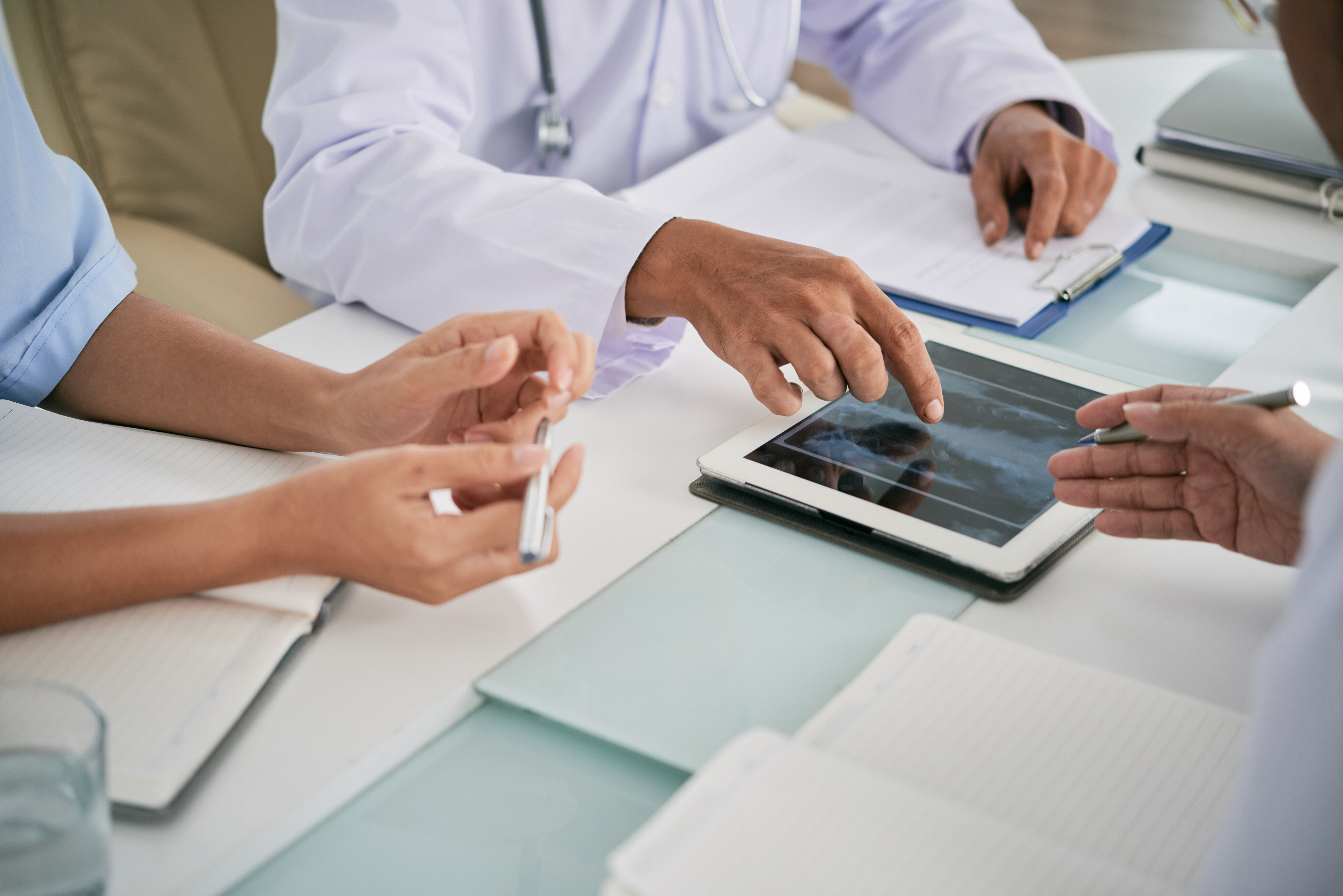 Close-up image of medical workers discussing lungs x-ray on tablet computer