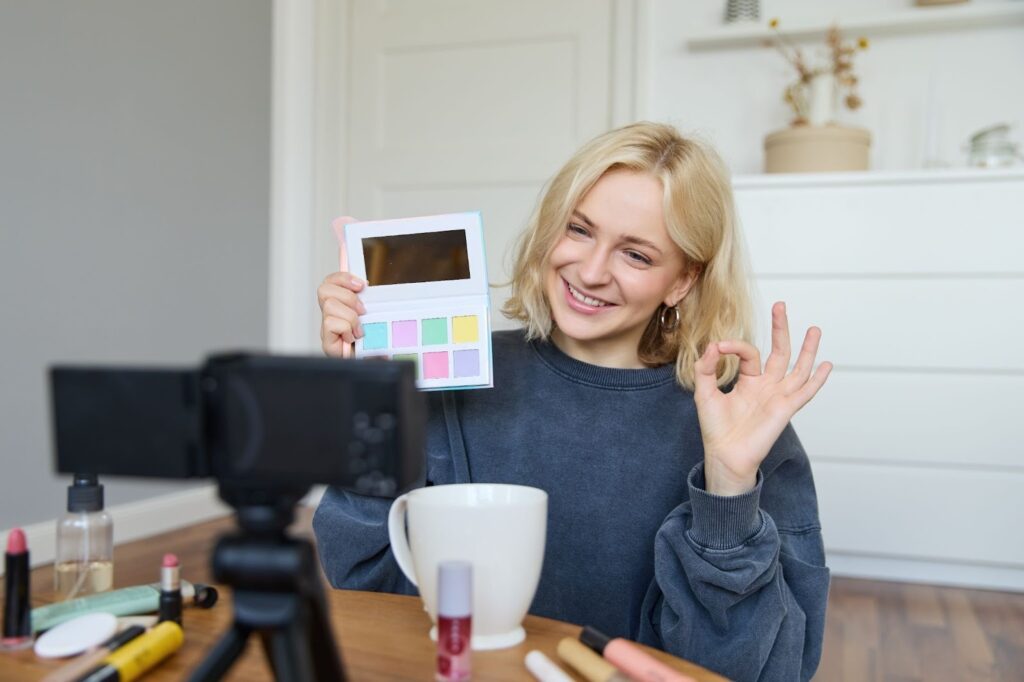Portrait of a beautiful smiling woman recording a video in her room, with the camera on the coffee table, checking